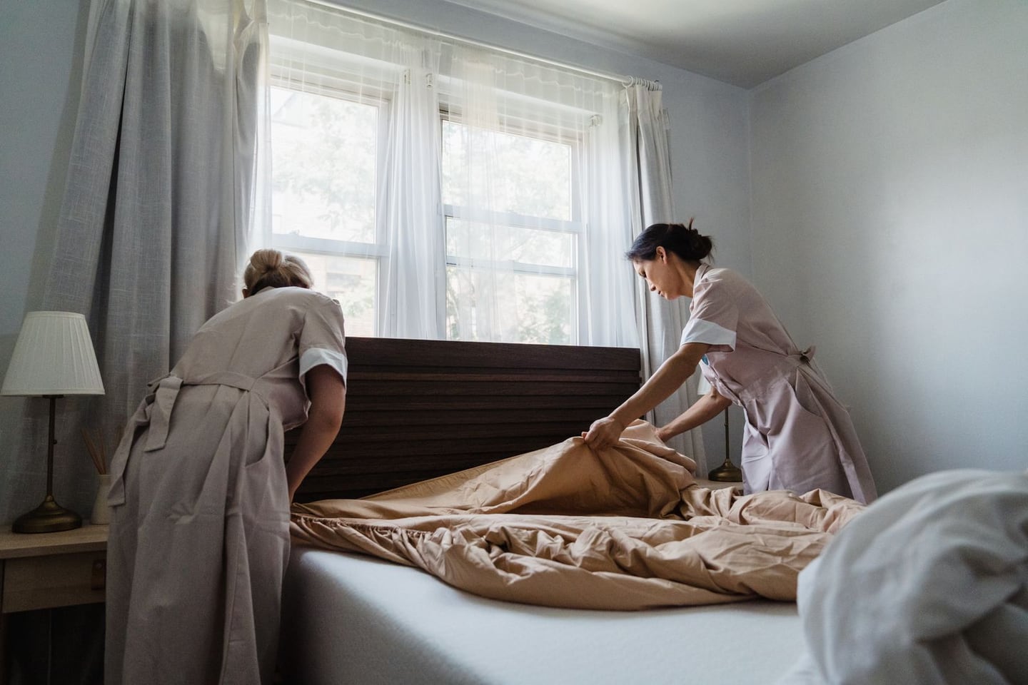Two housekeepers making a hotel bed
