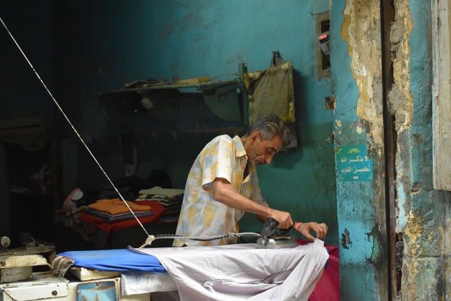 Man ironing in a street-corner laundry shop